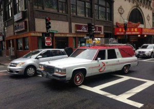 The Ghostbusters Ecto-1 car on a city street.