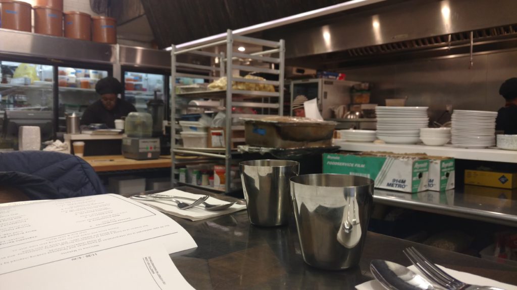 Andy and his husband eat brunch seated inside the restaurant kitchen.