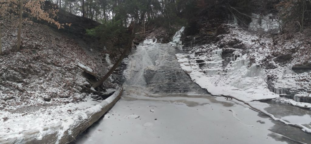 Wide view of frozen Buttermilk Falls in winter.