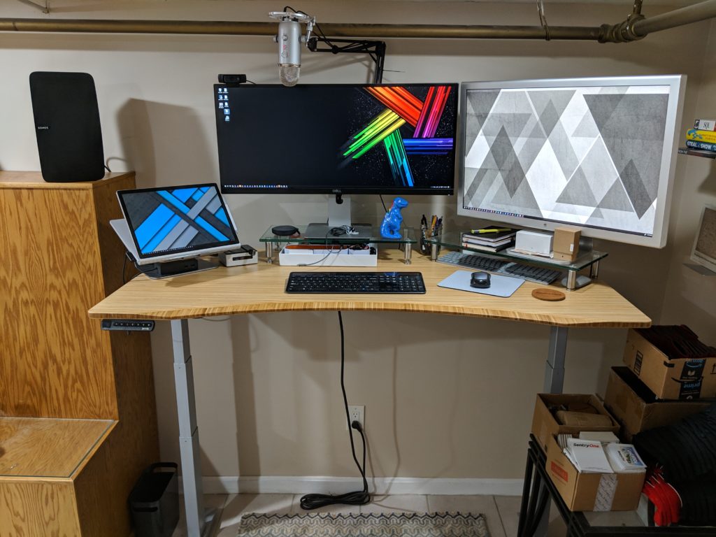 Wide view of a tidy home office desk with monitors, laptop, keyboard, and other equipment.