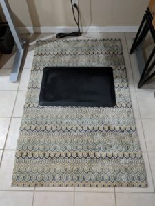 A rug and cushioned standing mat on the home office floor.