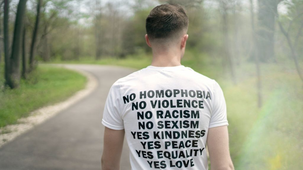 Person wearing a shirt printed with messages supporting equality and inclusion.